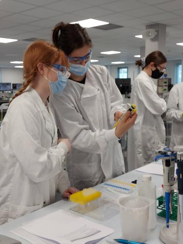 Two students in lab coats running experiments
